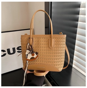 Dettaglio della borsa tote intrecciata color cammello con ciondolo a cavallo e logo