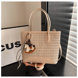 Dettaglio della borsa tote intrecciata beige con base liscia e ciondolo a cavallo