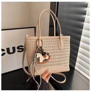 Dettaglio della borsa tote in trama beige con ciondolo a forma di cavallo di Troia