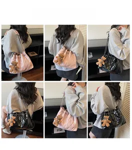 Detail of quilted bucket bag with chain strap and cute plush bear charm decoration