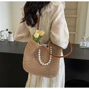 Detail of straw tote bag with pearl handle and leather strap on a floral dress