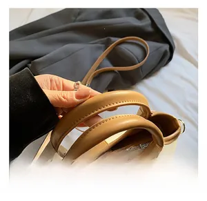 Close-up of comfortable handles on a two-tone beige bucket bag with metal hardware