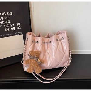 Detail of pink quilted patent bucket bag with chain strap and teddy bear charm
