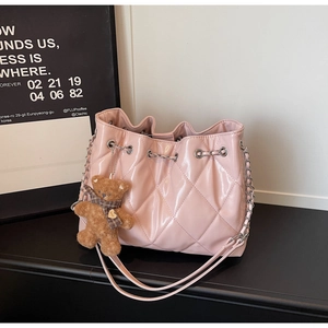 Detail of pink quilted bucket bag with silver chain and cute teddy bear charm accessory