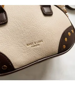 Close-up of lychee grain leather handbag with gold rivets and pearl strap detail