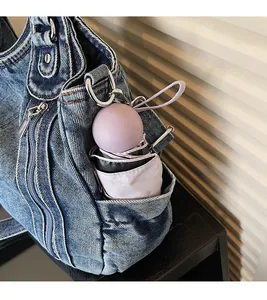 Detail of the side pocket on a dark blue denim tote bag with a purple capsule umbrella inside