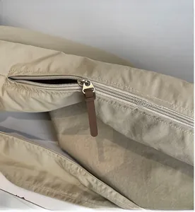 Détail de fermeture éclair en métal lisse avec tirette en cuir marron sur sac kaki