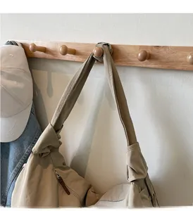 Détail du sac beige avec bandoulière large nouée et texture en tissu nylon résistant