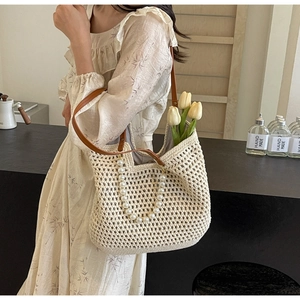Detail of hand-woven straw tote with pearl handle and brown leather straps on a floral dress