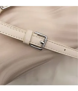 Close-up of beige leather shoulder strap with silver buckle and refined stitching detail