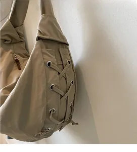 Détail du sac en nylon kaki avec laçage latéral et œillets métalliques élégants