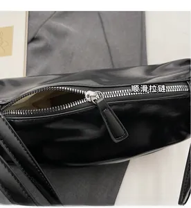 Close-up of smooth silver metal zipper and soft black leather on a chic underarm bag