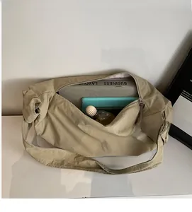 Vue de dessus montrant l'intérieur spacieux du sac besace kaki avec livre et tablette