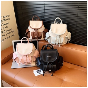 Detailed display of vintage drawstring backpacks in four colors on a leather sofa