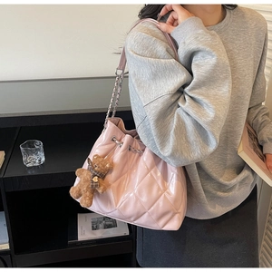 Close-up of pink quilted bucket bag with silver chain and cute teddy bear charm