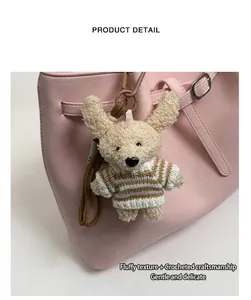 Détail d'un porte-clé chien en peluche avec pull rayé sur un sac à main rose