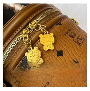 Détail du sac seau en cuir marron avec imprimé ours et fermetures éclair dorées ours