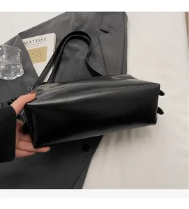 Detail view of a black matte leather underarm bag with double straps and metal buckles