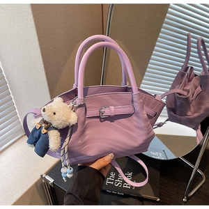 Purple faux leather handbag with wave texture and cute bear pendant on mirrored counter