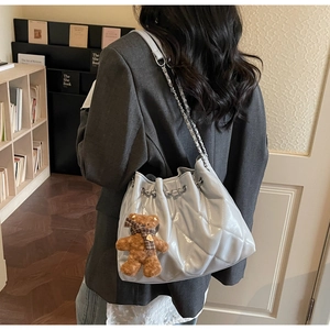 Detailed view of quilted leather bucket bag with chain strap and teddy bear charm