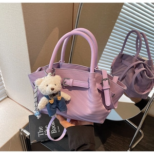 Detail of lavender purple handbag with metallic buckle and plush bear pendant accessory