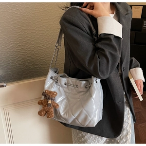 Quilted bucket bag in light blue faux leather featuring a cute teddy bear charm