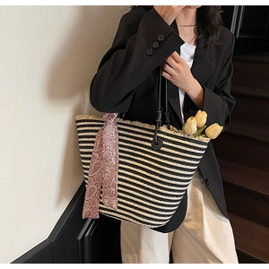 Detail of striped woven tote with fringe edges and paisley scarf on the handle