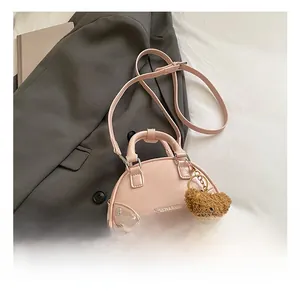 Detail of pink shell bag with rivet accents, teddy bear charm and fashion text