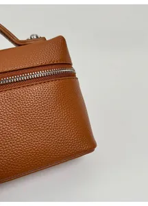 Détail de la texture cuir litchi beige avec fermeture éclair argentée et coutures soignées