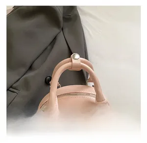 Detail of pink faux leather handbag handle showing reinforced metal hardware and stitching