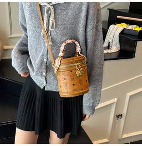 Détail du sac seau marron avec imprimé ours et foulard en soie fleuri sur la poignée