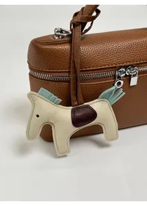 Gros plan d'un charme de sac cheval en cuir sur un sac à main à texture litchi