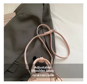 Detail of pink glossy handbag featuring a detachable and adjustable leather shoulder strap