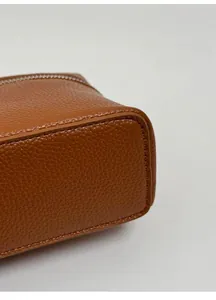Détail du cuir grainé marron caramel et de la base renforcée du sac à main en gros plan
