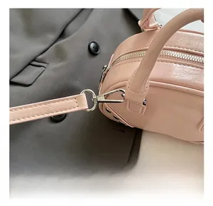 Close-up of the shiny silver metal lobster clasp on the pink crinkled leather handbag