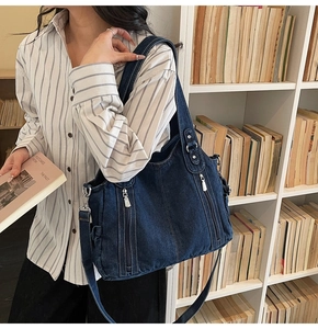 Detail view of navy blue denim tote bag with silver zippers in a vintage library setting