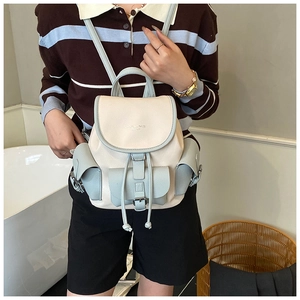 Detail of colorblock mini backpack in beige and light blue worn by model for style view