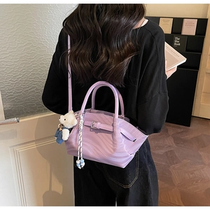 Detail view of lavender faux leather crossbody bag with teddy bear charm and textured finish