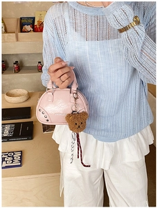 Detailed shot of a pink mini bowling bag with crinkled texture and plush bear charm