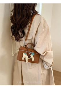 Détail arrière d'un sac boîte en cuir marron grainé avec un charmant pendentif cheval