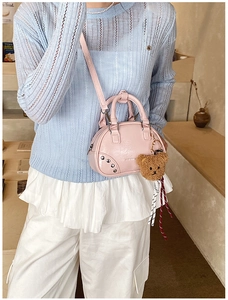 Detail of pink PU leather bowling bag featuring metal studs and a brown bear charm