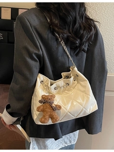 Glossy white quilted bucket bag with silver chain strap and plush bear charm decoration