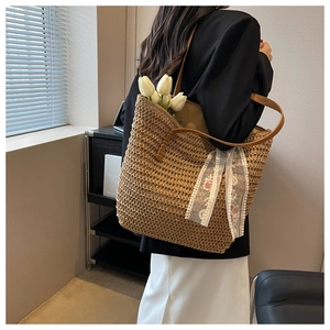 Detail of woven straw bucket bag with floral lace scarf and brown leather shoulder straps
