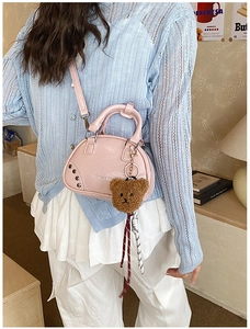 Pink leather bowling bag with teddy bear charm and studded side detail shown by model