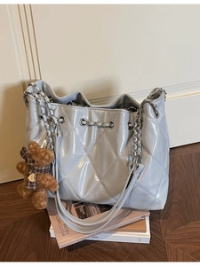 Light blue quilted bucket bag with silver chain straps and a plush bear charm accessory
