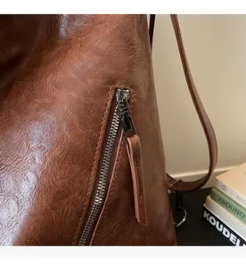 Detail of smooth gunmetal zipper and dark brown leather texture on versatile backpack