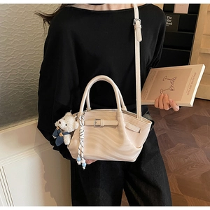 Detail of beige PU leather crossbody bag with wave texture and cute teddy bear pendant