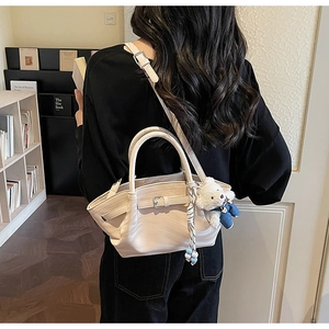 Detail of beige leather tote bag with adjustable side buckles and cute bear charm