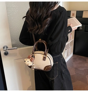Detail of lychee pattern handbag with cute teddy bear charm and brown leather trim
