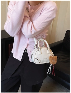 Detail view of white mini bowling bag with cute bear charm and fashion text print